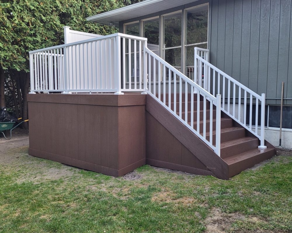 Brown composite back deck with white aluminum balusters off sliding doors in Kinburn