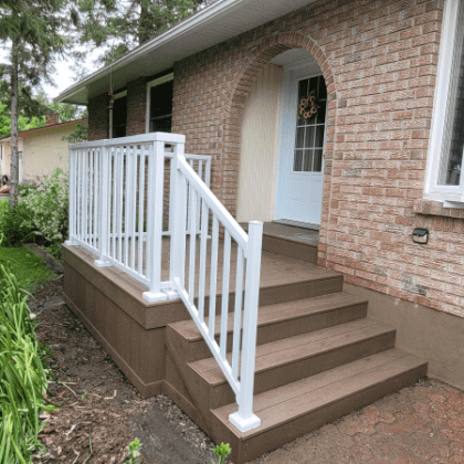 Brown composite front entrance stoop with white aluminum railings in Kinburn