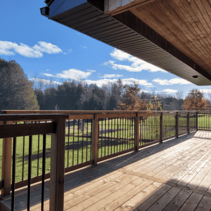 Pressure-treated front porch with black aluminum baluster railing in Drummond/North Elmsley