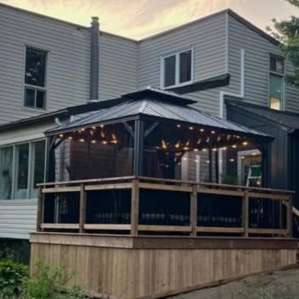 Pressure-treated deck with black aluminum balusters and aluminum gazebo, attached to side of house walkout in Pakenham